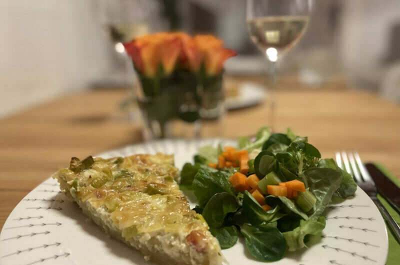Quiche Lorraine - Ein sStück Quiche mit Salat und einem Glas Wein.